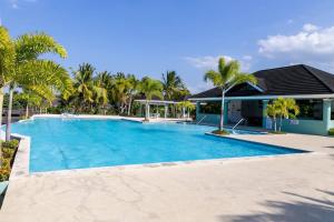 a swimming pool with palm trees and a house at Choose To Be Happy at The Palms Richmond Estates Villa #170 - 3-BR w Pool in Banks