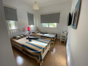 two beds in a room with two windows at Villa Diana - 200 meters from Kapparis, Fireman's Beach in Paralimni