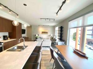 a kitchen and living room with a sink and a table at Brand New 3-Bedroom Condo in the Heart of Sidney in Sidney