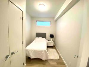 a small bedroom with a bed and a window at Brand New 3-Bedroom Condo in the Heart of Sidney in Sidney