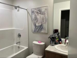 a bathroom with a toilet and a sink and a painting at Brand New 3-Bedroom Condo in the Heart of Sidney in Sidney +7 photos