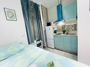 una pequeña cocina con armarios azules y una cama en una habitación en Fantastico Apartamento Estudio Centro, en Madrid