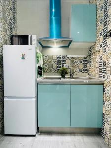 cocina con armarios azules y nevera blanca en Fantastico Apartamento Estudio Centro, en Madrid