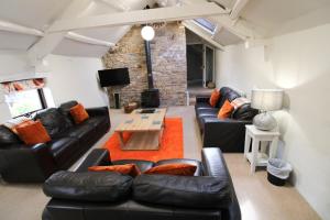 ein Wohnzimmer mit schwarzen Ledersofas und einem Tisch in der Unterkunft Brae Fell Cottage, Sebergham, Nr Caldbeck in Sebergham