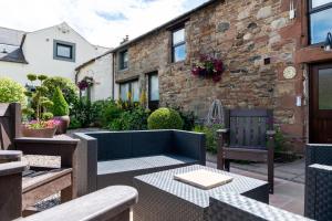 eine Terrasse mit einem Sofa und Stühlen sowie ein Gebäude in der Unterkunft Brae Fell Cottage, Sebergham, Nr Caldbeck in Sebergham