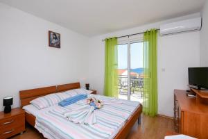 1 dormitorio con cama, TV y balcón en Lulak Studio Apartments, en Orebić