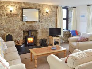 a living room with a stone wall with a fireplace at Bishop Rock - Grl in Trevilley