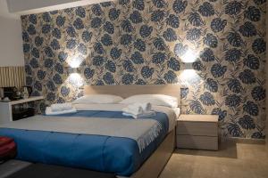 a bedroom with a bed with blue sheets and wallpaper at Dolce Vita in Messina
