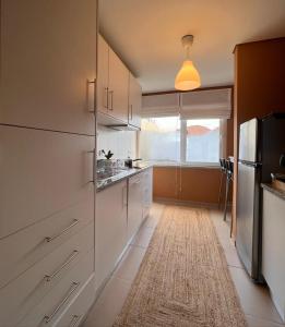 a kitchen with white cabinets and a large window at Douro Valley Terrace Apartments in Armamar