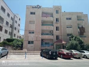 a building with cars parked in a parking lot at Decapolis in Irbid