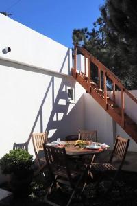 einen Tisch mit 3 Stühlen und eine Holztreppe in der Unterkunft Pé na Praia in Torres Vedras