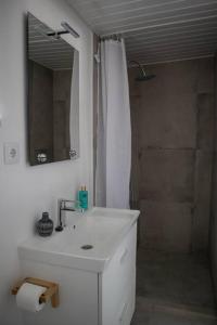 ein weißes Bad mit einem Waschbecken und einer Dusche in der Unterkunft Pé na Praia in Torres Vedras
