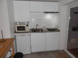 a kitchen with white cabinets and a microwave at Pé na Praia in Torres Vedras