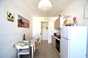 eine Küche mit einem Tisch und einem weißen Kühlschrank in der Unterkunft Pt57 Casa vacanza per 4 pax Alba in Torre dell'Orso + 18 Fotos