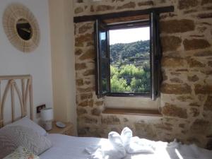1 dormitorio con ventana en una pared de piedra en La Esencia Casa Rural, en Cortes de Arenoso