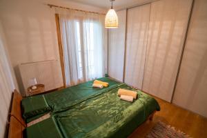 a bedroom with a green bed with two pillows on it at Tri pera -- self check in in Osijek