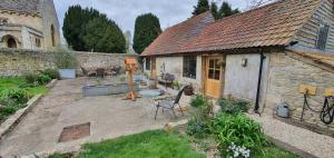 Luxury Barn House - Central Oxford/Cotswolds في Cassington: حديقة خلفية لبيت حجري مع فناء