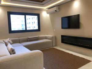 een woonkamer met een bank en een flatscreen-tv bij Chez Nissrine in Tetouan