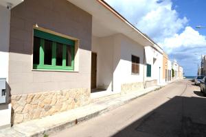 ein Gebäude mit einem grünen Fenster an einer Straße in der Unterkunft Ll84 Casa vacanze per 4 pax Luce in Roca Vecchia