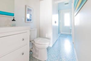 a white bathroom with a toilet and a shower at Seahorse Cottage in Indian Harbour
