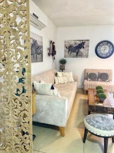 un soggiorno con divano e orologio sul muro di על קצה ההר a Yoqne‘am