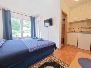 a bedroom with a blue bed and a kitchen at Dom M Apartments in Budva