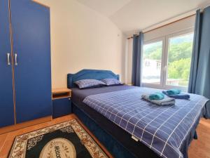 ein Schlafzimmer mit einem blauen Bett und einem Fenster in der Unterkunft Dom M Apartments in Budva