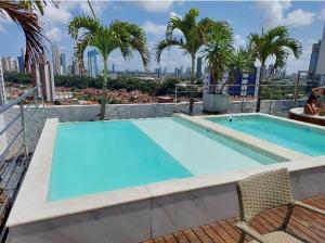 uma piscina no topo de um edifício com palmeiras em Flat encantador no Manaira Apart Hotel 1301 em João Pessoa