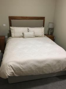 1 dormitorio con 1 cama grande con sábanas y almohadas blancas en Cuckoos Corner en Teach Munna