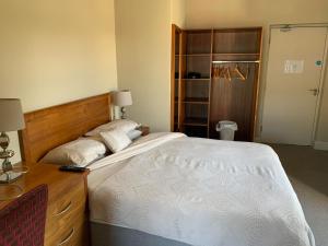 ein Schlafzimmer mit einem großen Bett und einer Holzkommode in der Unterkunft Cuckoos Corner in Teach Munna