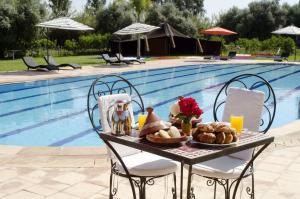 una mesa con comida junto a una piscina en Palais Riad Berbère en Marrakech