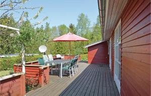a wooden deck with a table and an umbrella at 3 Bedroom Cozy Home In Fårvang in Fårvang
