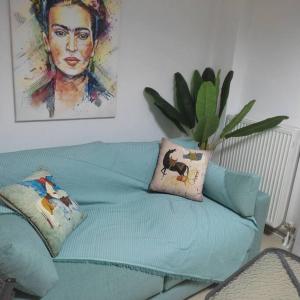 歐雷提亞達的住宿－Φρίντα στο κέντρο της Ορεστιάδας，一张带枕头的绿色沙发以及墙上的绘画作品