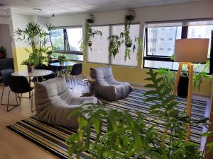 ein Wohnzimmer mit Sofas, Pflanzen, Tischen und Fenstern in der Unterkunft Bewiki in Florianópolis