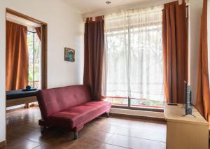 a living room with a red couch in front of a window at Mundaka : Burnt Toast Surfcamp in Nosara