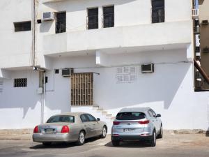 شقة جمان طيبة Joman Taibah Apartment في المدينة المنورة: سيارتين متوقفتين أمام مبنى أبيض