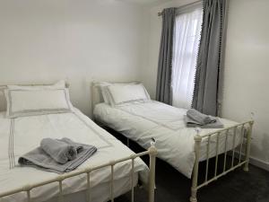 two twin beds in a room with a window at Cottage, 10 mins Train / River in Burnham-on-Crouch