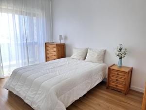 a bedroom with a bed and a dresser and a window at Mar no Horizonte in Costa da Caparica