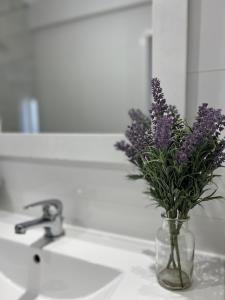 a vase of purple flowers sitting on a sink at Mar no Horizonte in Costa da Caparica