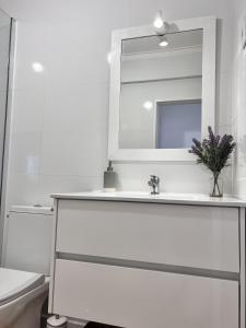 bagno bianco con lavandino e specchio di Mar no Horizonte a Costa da Caparica
