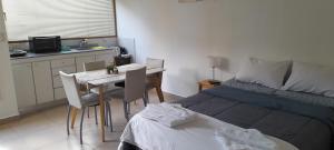 1 dormitorio con 1 cama, mesa y sillas en Castor Fueguino: departamento cálido, céntrico y equipado - Wi Fi en Ushuaia