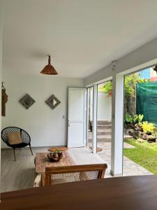 a living room with a table and chairs and sliding glass doors at Ti Bwa Lodge, bas de villa cosy, piscine & vue mer in Capesterre-Belle-Eau