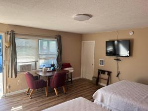 a hotel room with a table and a tv on the wall at Great House Motel in Sequim