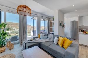 sala de estar con sofá gris y almohadas amarillas en Villa Mare Syros en Finikas