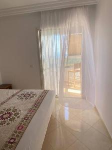 um quarto com uma cama e uma janela com uma cadeira em Nice apartment beach front, close to Rabat main sightseeing. Fiber WiFi em Rabat