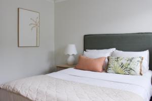 a bedroom with a white bed with a green headboard at Mirage Luxury Beachside 3 Bedroom Apartment in Alexandra Headland