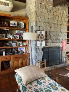 sala de estar con pared de piedra y chimenea en Casa Colonial La Alegria en Tandil
