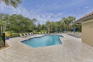 a swimming pool in a yard with chairs and trees at Ground Floor Convenient Gated Condo At Beach Sawgrass - Pet Friendly!!! in Ponte Vedra Beach