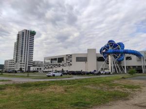 a large building with a blue ferris wheel in a parking lot at Apartament Szmaragdowy Light Tower Aquapark Reda in Reda