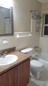 La salle de bains est pourvue d'un lavabo, de toilettes et d'une baignoire. dans l'établissement Glam 2 Bedroom Apartment Close to NSU in Cooper City, à Cooper City